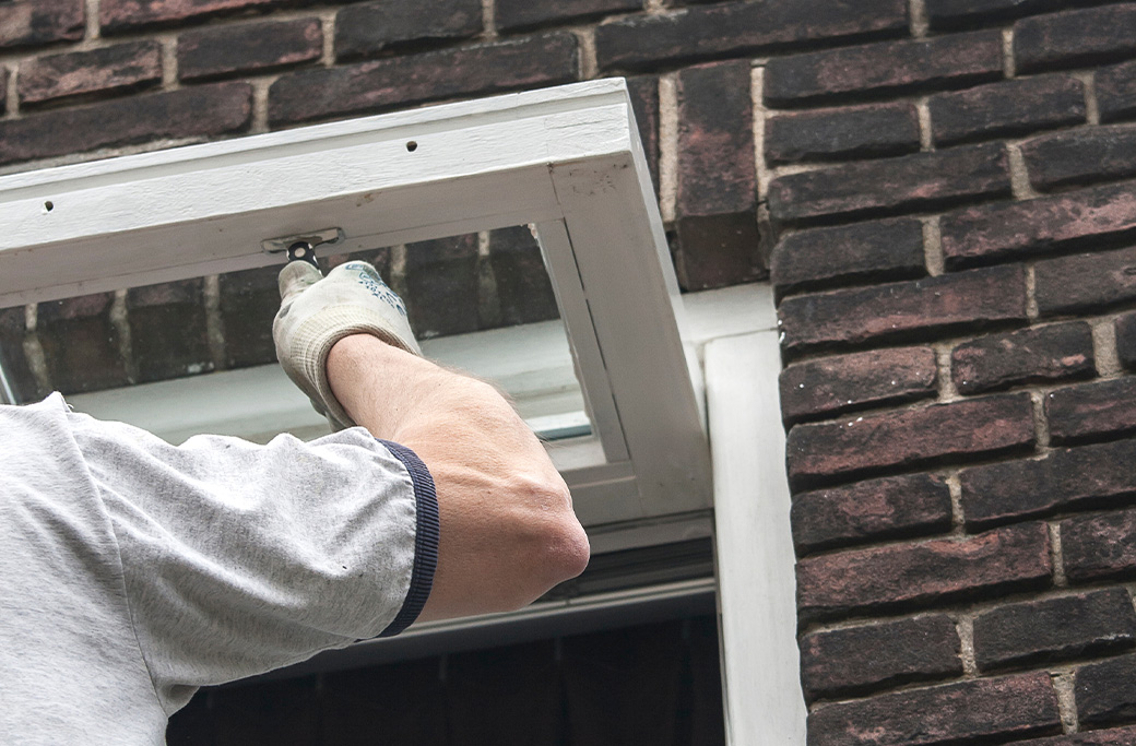 Painter preparing peeling exterior trim before applying new paint